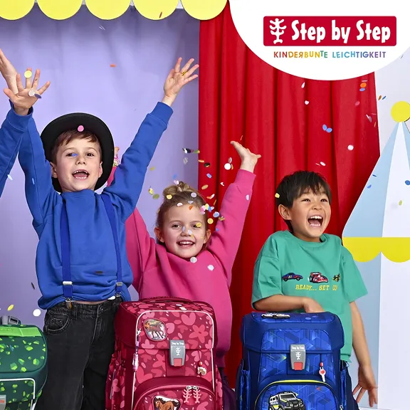 Fünf Kinder vor einer Theaterkulisse mit Schulranzen vorwerfen mit Konfetti.